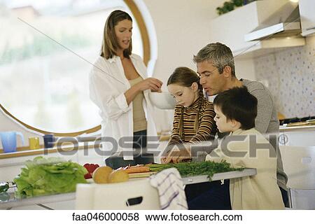 Family together in kitchen, father helping daughter cut vegetables View Large Photo Image Stock Photo - Family together in kitchen, father helping daughter cut vegetables. Fotosearch