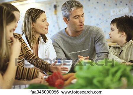 Family together in kitchen, raw vegetables on counter View Large Photo Image Stock Photograph - Family together in kitchen, raw vegetables on counter. Fotosearch