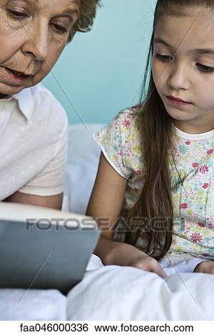 Grandmother reading to granddaughter View Large Photo Image Stock Photograph - Grandmother reading to granddaughter. Fotosearch