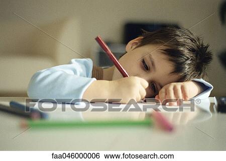 Little boy resting head on arm, drawing with colored pencils View Large Photo Image Stock Photograph - Little boy resting head on arm, drawing with colored pencils. Fotosearch
