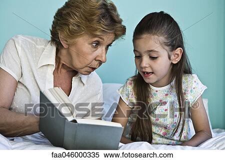 Stock Photography - Little girl reading book with grandmother. Fotosearch