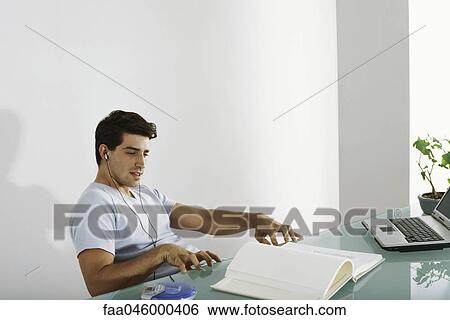 Man at desk listening to music, pretending to play piano along with song View Large Photo Image Stock Photograph - Man at desk listening to music, pretending to play piano along with song. Fotosearch