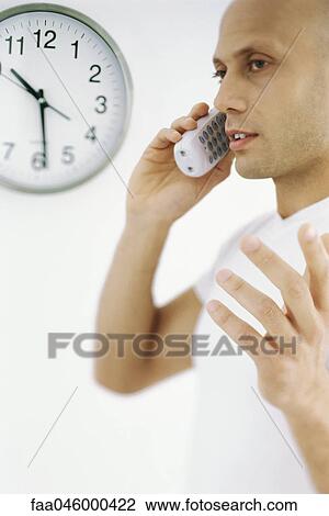 Stock Image - Man on phone call, clock in background. Fotosearch