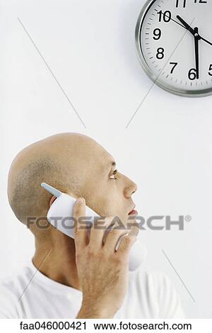 Man on phone call, looking over shoulder at clock View Large Photo Image Stock Image - Man on phone call, looking over shoulder at clock. Fotosearch