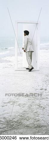 Man opening and entering door placed on beach View Large Photo Image Stock Photograph - Man opening and entering door placed on beach. Fotosearch