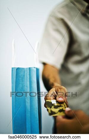 Stock Photography - Man paying for purchase with credit card, cropped, close-up. Fotosearch