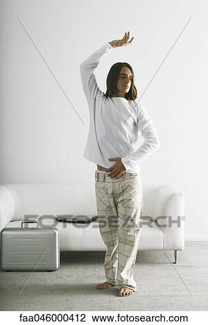 Stock Image - Man standing with one arm raised, eyes closed. Fotosearch