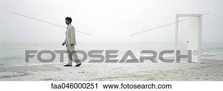 Man walking hesitantly along beach, open doorway in background View Large Photo Image Stock Image - Man walking hesitantly along beach, open doorway in background. Fotosearch