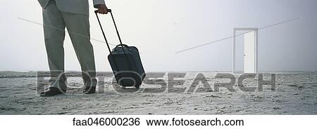 Man walking with rolling luggage on beach, open door in distance View Large Photo Image Stock Photograph - Man walking with rolling luggage on beach, open door in distance. Fotosearch