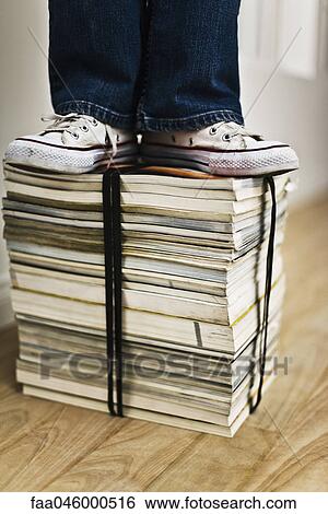 Person standing on top of bound stack of books and magazines View Large Photo Image Stock Photograph - Person standing on top of bound stack of books and magazines. Fotosearch