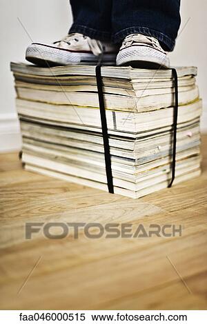 Person standing on top of bound stack of books and magazines View Large Photo Image Stock Photography - Person standing on top of bound stack of books and magazines. Fotosearch