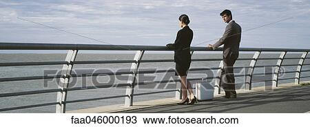 Professional colleagues at waterfront railing looking at view, briefcase on sidewalk between them View Large Photo Image Stock Image - Professional colleagues at waterfront railing looking at view, briefcase on sidewalk between them. Fotosearch