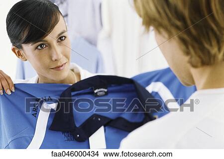 Saleswoman holding up shirt for shopper's approval View Large Photo Image Picture - Saleswoman holding up shirt for shopper's approval. Fotosearch