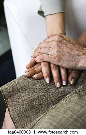 Stock Image - Senior woman holding adult daughter's hand, close-up. Fotosearch