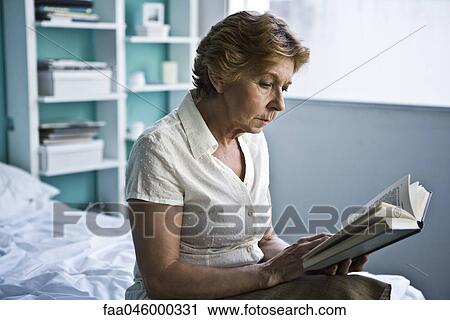 Senior woman sitting on bed reading book View Large Photo Image Stock Image - Senior woman sitting on bed reading book. Fotosearch