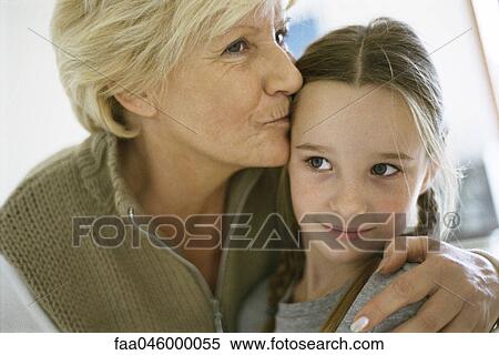 Senior woman with arm around granddaughter, kissing forehead, portrait View Large Photo Image Stock Photography - Senior woman with arm around granddaughter, kissing forehead, portrait. Fotosearch