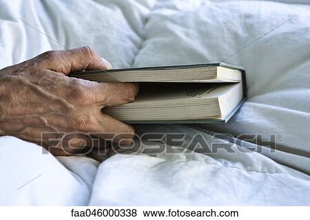 Stock Photo - Senior's hand holding book. Fotosearch