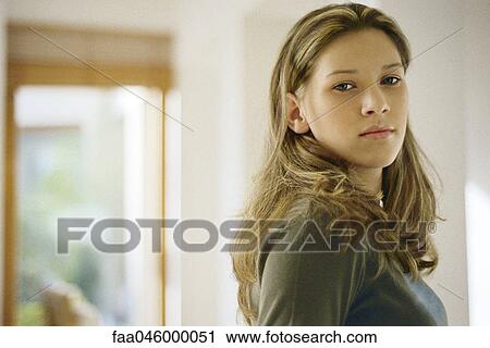 Stock Image - Teenage girl looking over shoulder, portrait. Fotosearch