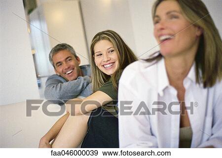 Teenage girl sitting with parents, all smiling, mother laughing View Large Photo Image Stock Photo - Teenage girl sitting with parents, all smiling, mother laughing. Fotosearch