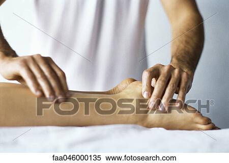 Stock Photography - Therapist treating patient's foot with acupressure. Fotosearch