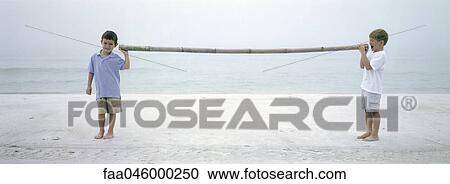 Two boys on beach talking to each other through length of bamboo View Large Photo Image Stock Image - Two boys on beach talking to each other through length of bamboo. Fotosearch