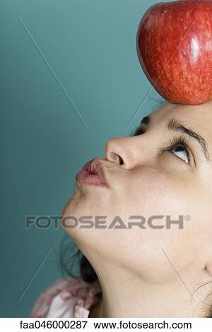 Woman balancing apple on forehead, puckering lips View Large Photo Image Stock Photo - Woman balancing apple on forehead, puckering lips. Fotosearch