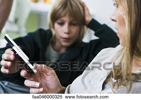 Woman handing cell phone to boy View Large Photo Image Stock Photography - Woman handing cell phone to boy. Fotosearch
