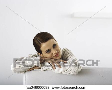 Woman leaning against armrest resting head on arms, portrait View Large Photo Image Stock Photo - Woman leaning against armrest resting head on arms, portrait. Fotosearch