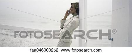 Woman leaning against doorway using cell phone View Large Photo Image Stock Image - Woman leaning against doorway using cell phone. Fotosearch