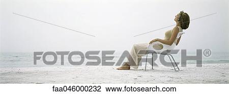 Stock Image - Woman listening to headphones on the beach. Fotosearch