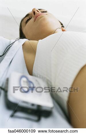 Woman lying on back listening to personal music player View Large Photo Image Stock Photo - Woman lying on back listening to personal music player. Fotosearch