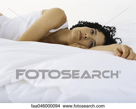 Woman lying on bed daydreaming View Large Photo Image Picture - Woman lying on bed daydreaming. Fotosearch