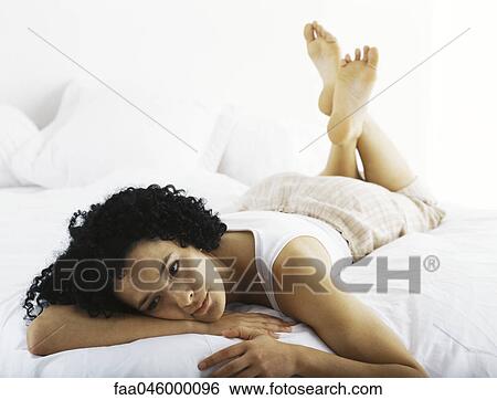 Stock Photograph - Woman lying on stomach daydreaming. Fotosearch