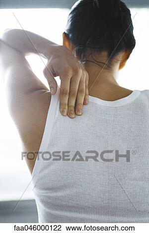 Woman massaging her shoulder, rear view View Large Photo Image Stock Image - Woman massaging her shoulder, rear view. Fotosearch