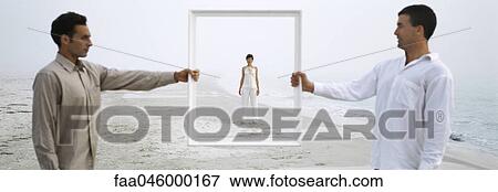 Stock Photo - Woman on beach seen through picture frame held up by two men. Fotosearch