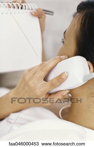 Woman on phone call looking at notepad View Large Photo Image Stock Image - Woman on phone call looking at notepad. Fotosearch