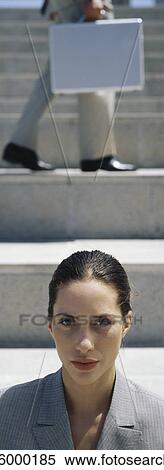 Stock Photography - Woman on steps, person walking across steps in background. Fotosearch