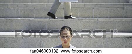 Woman on steps with eyes shut, businessman walking in background View Large Photo Image Stock Image - Woman on steps with eyes shut, businessman walking in background. Fotosearch