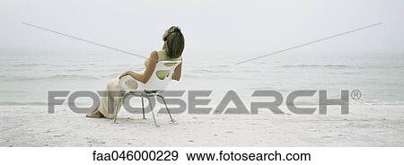 Stock Photo - Woman relaxing in chair on beach. Fotosearch