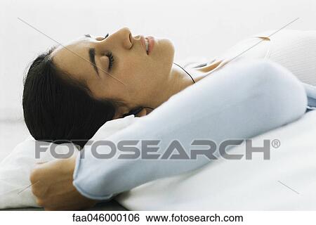Stock Photograph - Woman resting, listening to earphones. Fotosearch