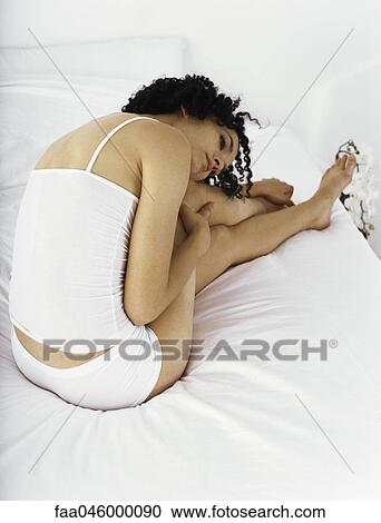 Woman sitting on bed with head resting on knee, looking away contemplatively View Large Photo Image Stock Image - Woman sitting on bed with head resting on knee, looking away contemplatively. Fotosearch