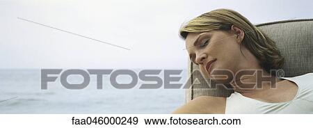 Woman sleeping in armchair, open sea in background View Large Photo Image Stock Photo - Woman sleeping in armchair, open sea in background. Fotosearch