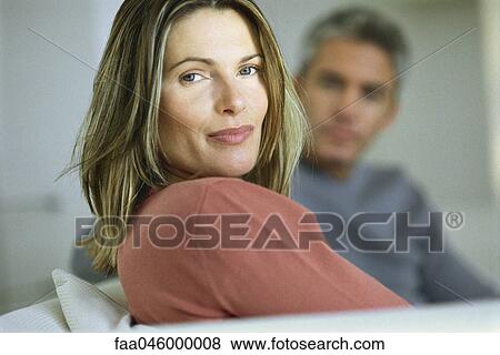 Woman smiling over shoulder at camera, man in background View Large Photo Image Stock Photo - Woman smiling over shoulder at camera, man in background. Fotosearch