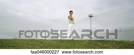 Woman standing in field using cell phone, briefcase on ground nearby View Large Photo Image Stock Photo - Woman standing in field using cell phone, briefcase on ground nearby. Fotosearch