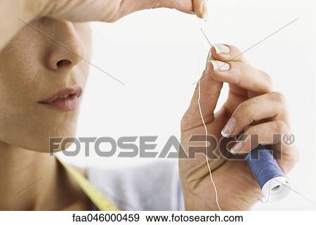 Stock Photo - Woman threading needle, cropped. Fotosearch