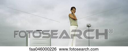 Woman using cell phone, briefcase in foreground, low angle view View Large Photo Image Stock Photograph - Woman using cell phone, briefcase in foreground, low angle view. Fotosearch