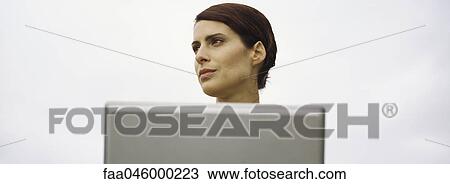 Stock Image - Woman with laptop, looking away. Fotosearch