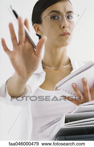 Stock Photo - Woman with notepad, gesturing not to interrupt work. Fotosearch