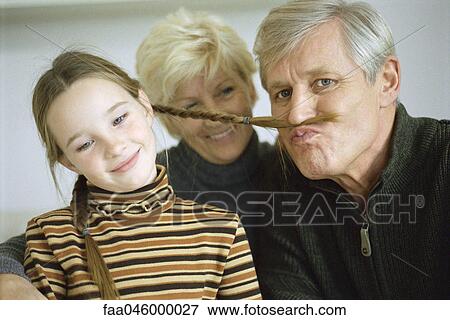Young girl with grandparents, grandfather using girl's braid to imitate mustache View Large Photo Image Stock Photo - Young girl with grandparents, grandfather using girl's braid to imitate mustache. Fotosearch