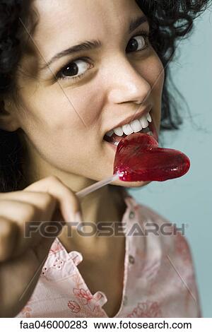 Young woman eating heart-shaped lollipop View Large Photo Image Stock Image - Young woman eating heart-shaped lollipop. Fotosearch